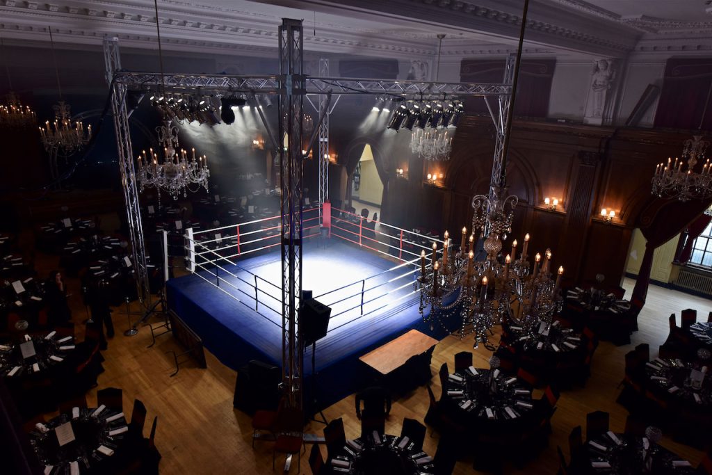 Professional boxing ring with truss lighting and stage lighting set up inside a grand event venue for a corporate boxing event, demonstrating corporate AV production